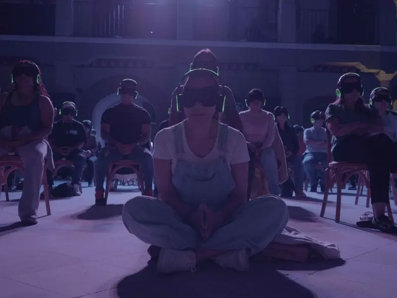 Personas meditando con audífonos en la experiencia
